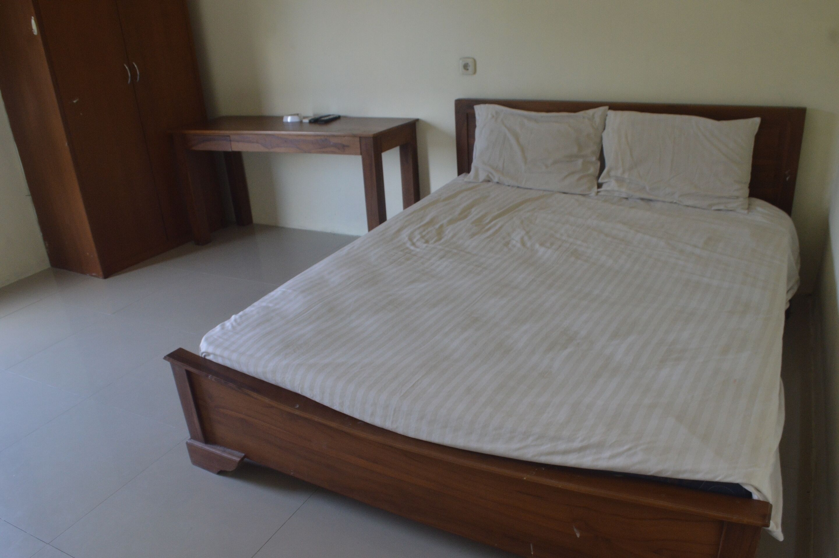 A bedroom with a wooden bed, a bedside table, and a wardrobe.
