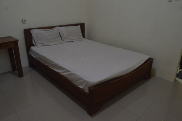 A single bed with a wooden frame and white bedding in a room with white walls and a tiled floor. - Hotel O Wisma Nusantara Near SD GMIM Wiau Lapi (Sulta)