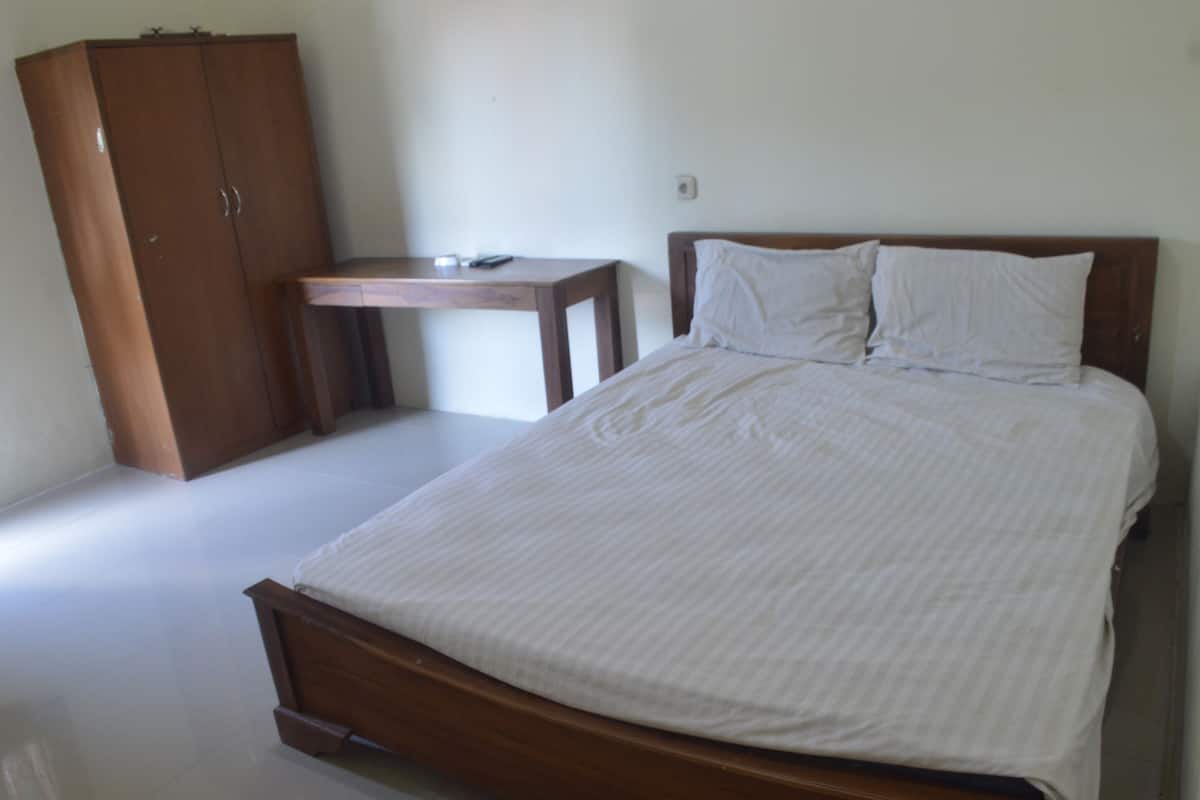 Une chambre à coucher avec un lit, une armoire en bois et une petite table.