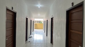 A hallway with two doors on each side, leading to a bright room with a yellow wall and a window.
