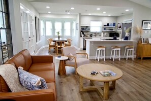 Una cocina moderna con una isla central, suelo de madera y un área de comedor con mesa y sillas.