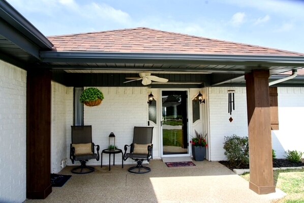 A covered patio with two chairs, a table, and a ceiling fan. - Waterfront • Kayaks • Game Room • Sunsets (Granbury)