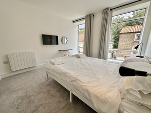 Relax in a cozy space with a neatly made bed, flat-screen TV, and window with a view of the surrounding area.