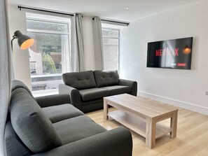 Relax in this inviting living space with a large window, flat-screen TV, and comfortable seating area.