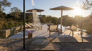 A patio with a water feature, two umbrellas, and lounge chairs. - Euphonia Residence by Athina Hospitality (Ermionida)