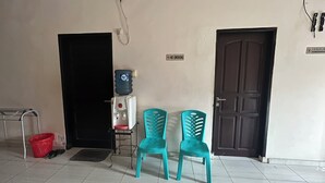 A room with a water dispenser, two chairs, a red trash bin, and a closed door. - Hotel O Losmen Bahalap Syariah MarabahanNearSiring Marabahan (Ulek Barito) (Banjarmasin)
