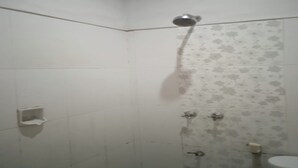 A shower with a handheld showerhead, a toilet, and a small shelf unit. - Hotel O Losmen Bahalap Syariah MarabahanNearSiring Marabahan (Ulek Barito) (Banjarmasin)