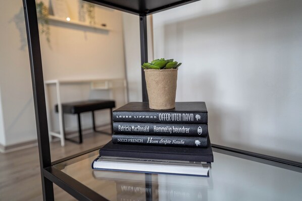 A stack of books with a potted plant on top, placed on a glass table. - Central BnB Apartment Nr6 Stavanger 4 Bedrooms (Stavanger)