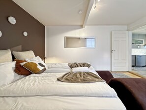 Relax in a spacious room with a large bed, a mirror above, and a kitchenette area.
