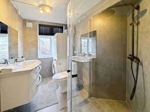 Enjoy a refreshing shower in the glass-enclosed shower with handheld showerhead, standalone toilet, and vanity with sink and mirror.