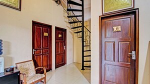 A hallway with two wooden doors, a chair, and a staircase. - OYO 92851 Homestay Borobudur Specpacker Syariah (Borobudur)
