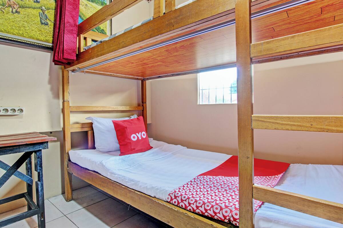 Une chambre avec un lit superposé en bois, une petite table et une fenêtre.