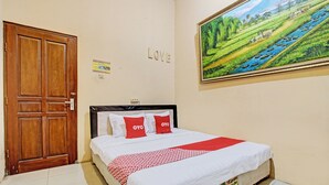 A bedroom with a wooden door, a bed with white and red bedding, a painting of a landscape, and a sign that says "LOVE". - OYO 92851 Homestay Borobudur Specpacker Syariah (Borobudur)