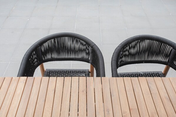 Two wicker chairs and a wooden table on a tiled patio.