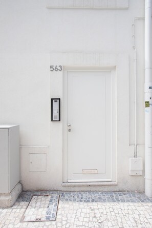 A white door with the number 563 on the wall, a mail slot, and a small electrical box.