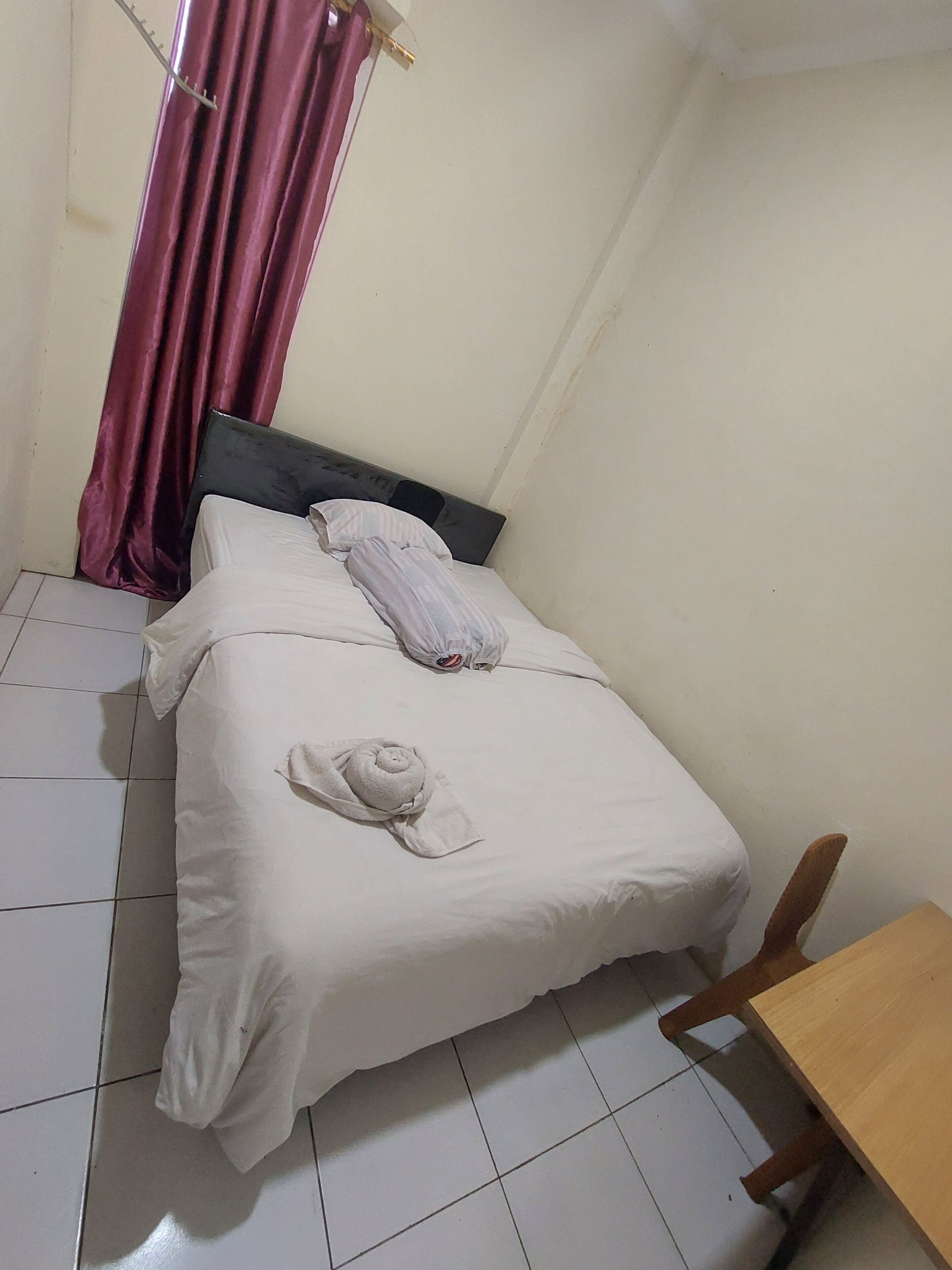 Una habitación pequeña y sencilla con una cama, una silla de madera y una mesa.