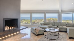 A modern living room with a fireplace, a sofa, and a view of the ocean. - 3906 Ocean's One Eleven ~ Unobstructed Ocean View! (Carmel)