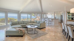 A spacious living room with a large sectional sofa, a coffee table, and a view of the ocean. - 3906 Ocean's One Eleven ~ Unobstructed Ocean View! (Carmel)