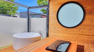 A modern bathroom with a wooden wall, a round window, and a bathtub.