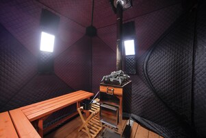 A cozy, insulated room with a wooden table, a small stove, and a quilted ceiling.