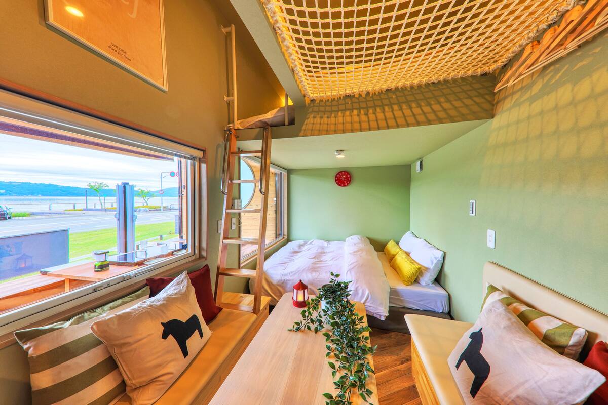 A cozy room with a bed, a bench, and a window overlooking a scenic view.