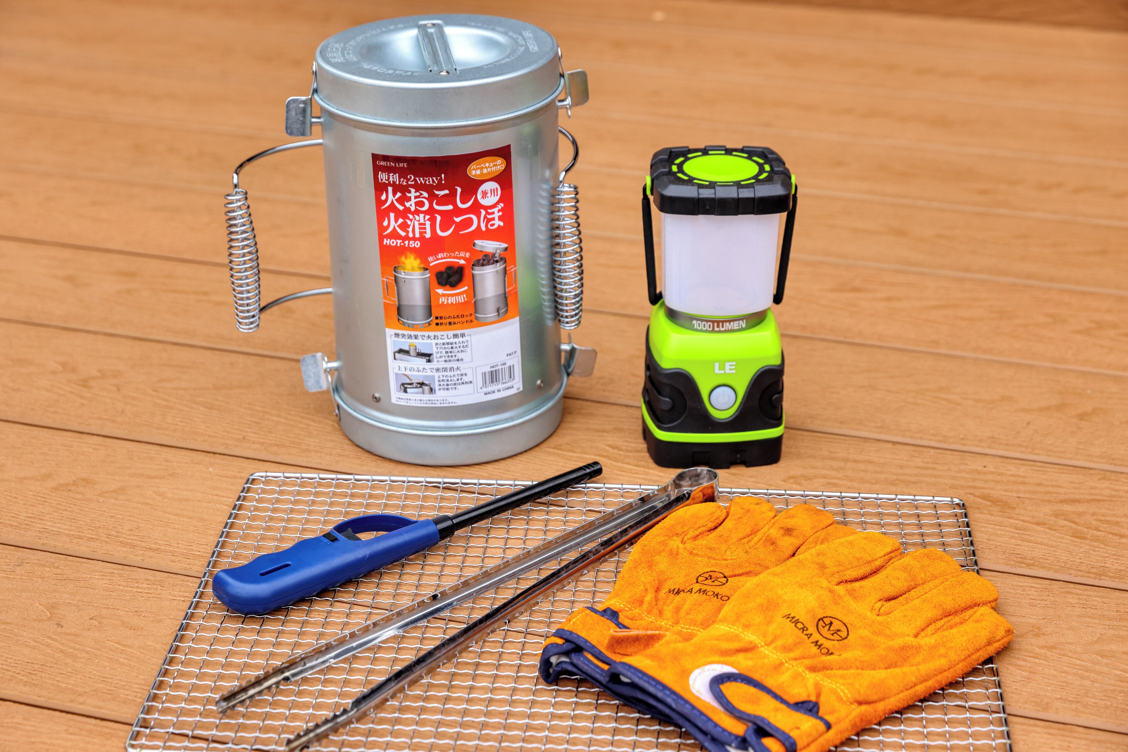A metal container with a label, a flashlight, a pair of gloves, and a tool on a wire rack.