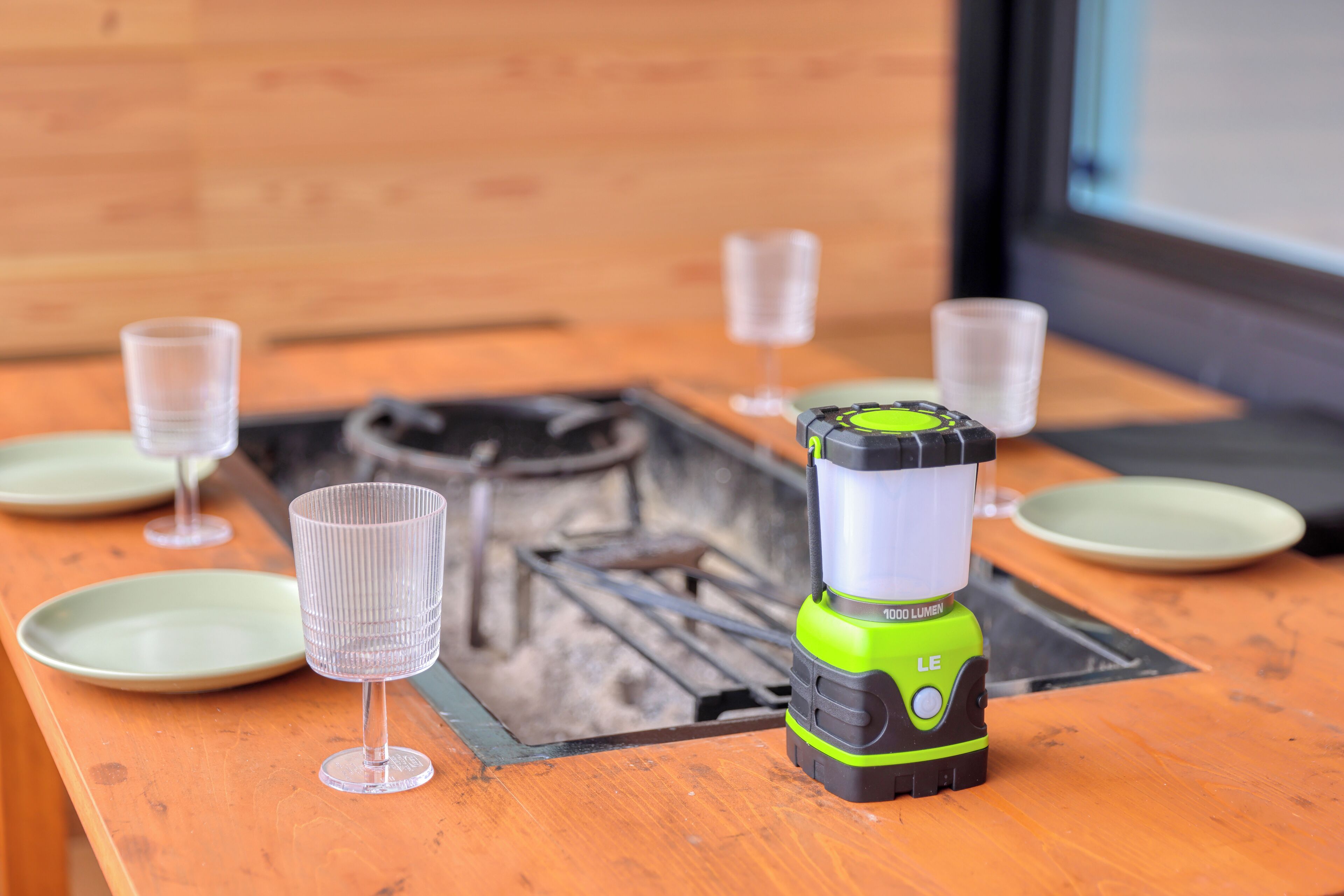 A table with a green and black flashlight, a glass, and a plate.