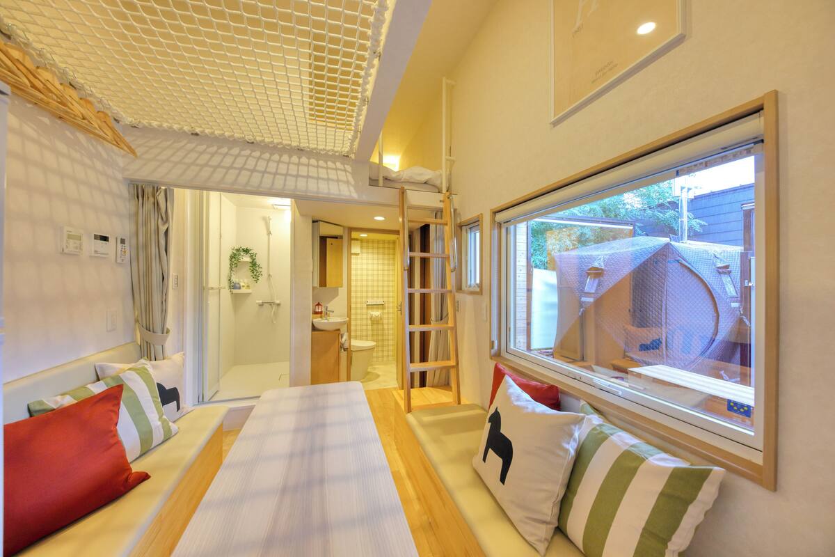 A hotel room with a bed, pillows, a window, and a view of the outside.