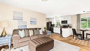 A modern living room with a brown sofa, ottoman, and a dining area with a table and chairs. - New! Comfortable 1BR Upper Flat, Roseville Downtown (Roseville)