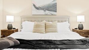 A neatly made bed with a striped pillow, a headboard, and two bedside tables with lamps. - New! Comfortable 1BR Upper Flat, Roseville Downtown (Roseville)