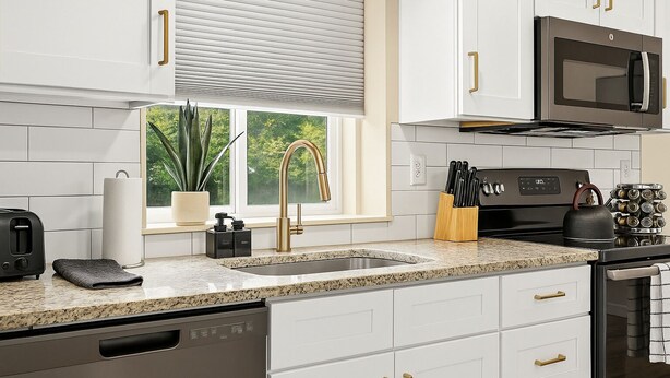 A modern kitchen with white cabinets, a stainless steel sink, a black stove, and a microwave. - Spacious 1BR End Unit, Heart of Roseville (Roseville)
