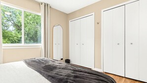 A bedroom with a bed, a window with curtains, and a wardrobe. - Spacious 1BR End Unit, Heart of Roseville (Roseville)