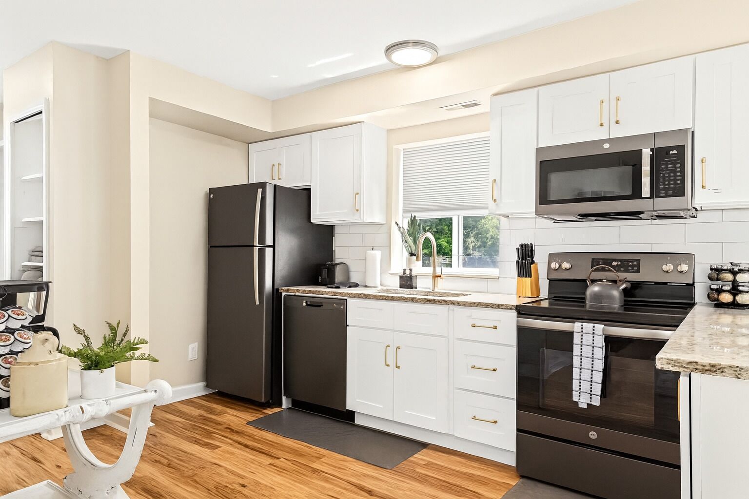 A modern kitchen with white cabinets, a black refrigerator, a microwave, and a stove.