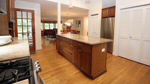 Una cocina con armarios de madera, encimera de granito, refrigerador de acero inoxidable y un comedor con mesa y sillas.