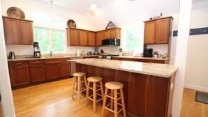 Una cocina con armarios de madera, una isla grande con taburetes, un microondas y una cafetera.