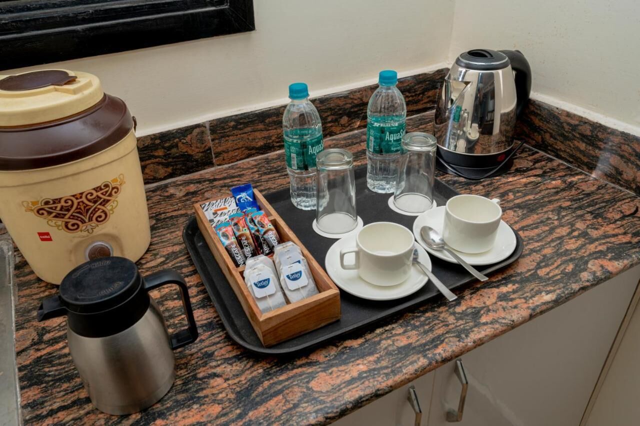 Eine Küchenzeile mit Kaffeemaschine, Wasserflaschen, Teebeuteln und einem Thermos auf einer Granitabdeckung.