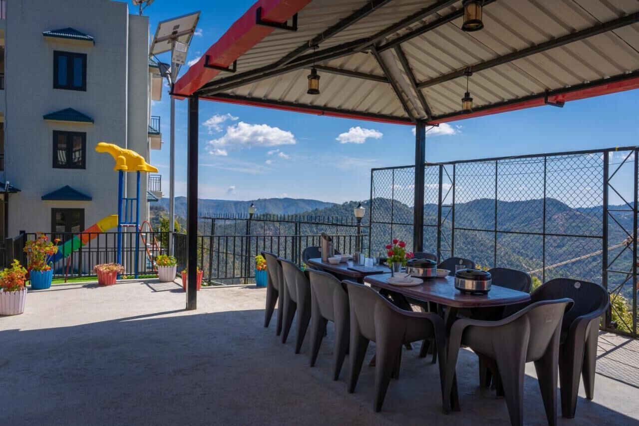 An outdoor dining area with a table and chairs, a yellow sculpture, and a view of mountains.