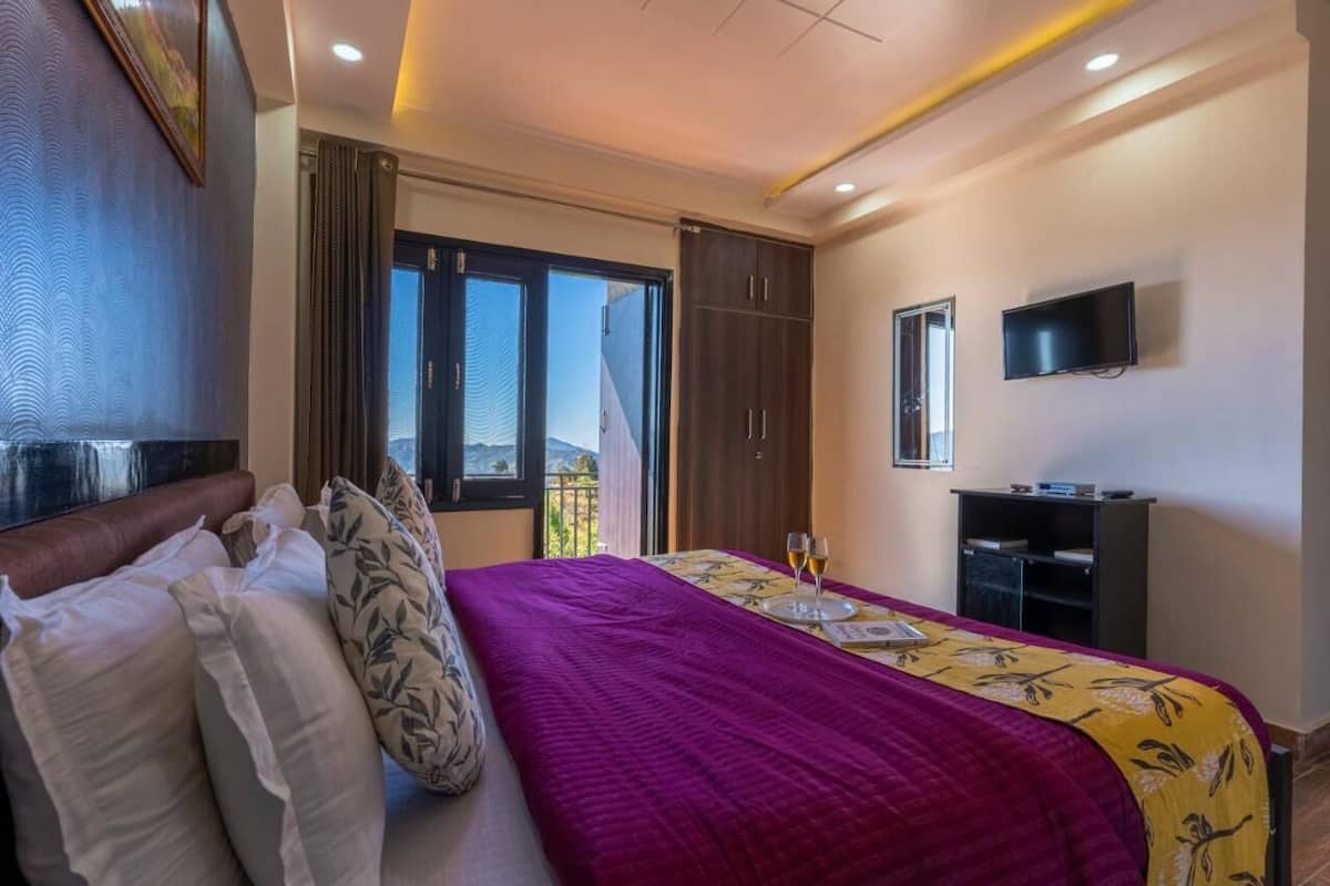 Une chambre d’hôtel équipée d’un lit, d’une télévision, d’un bureau et offrant une vue sur l’extérieur.