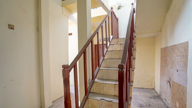 A staircase with wooden railings and beige tiled steps leading to an upper floor. - Hotel O Sunyoto Homestay Syariah (Mojosari)