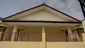 A building with a yellow facade, a pitched roof, and a covered porch with metal railings. - Hotel O Sunyoto Homestay Syariah (Mojosari)