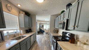 A modern kitchen with grey cabinets, a black stove, and a sink. - Recently Updated & Complete w/Golf Cart, Coffee Bar, & MORE! (The Villages)