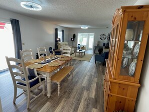 A dining area with a wooden table, white chairs, and a blue sofa.