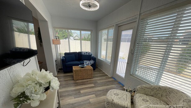 A modern living room with a blue sofa, a wicker coffee table, and two patterned armchairs. - Recently Updated & Complete w/Golf Cart, Coffee Bar, & MORE! (The Villages)