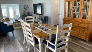 A dining area with a wooden table, white chairs, and a blue couch. - Recently Updated & Complete w/Golf Cart, Coffee Bar, & MORE! (The Villages)