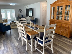 A dining area with a wooden table, white chairs, and a blue couch.