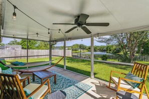 Un patio al aire libre con ventilador de techo, luces colgantes y una hamaca.