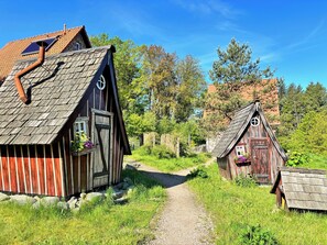 A rustic wooden building with a sloped roof, a chimney, and a small window.