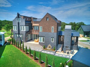 A multi-story house with a patio, outdoor seating, and a stone fireplace.