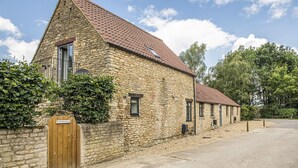 A stone building with a tiled roof, a wooden gate, and a sign that reads "The Milk House." - The Milking Parlour - Luxury Cottages (Malmesbury)