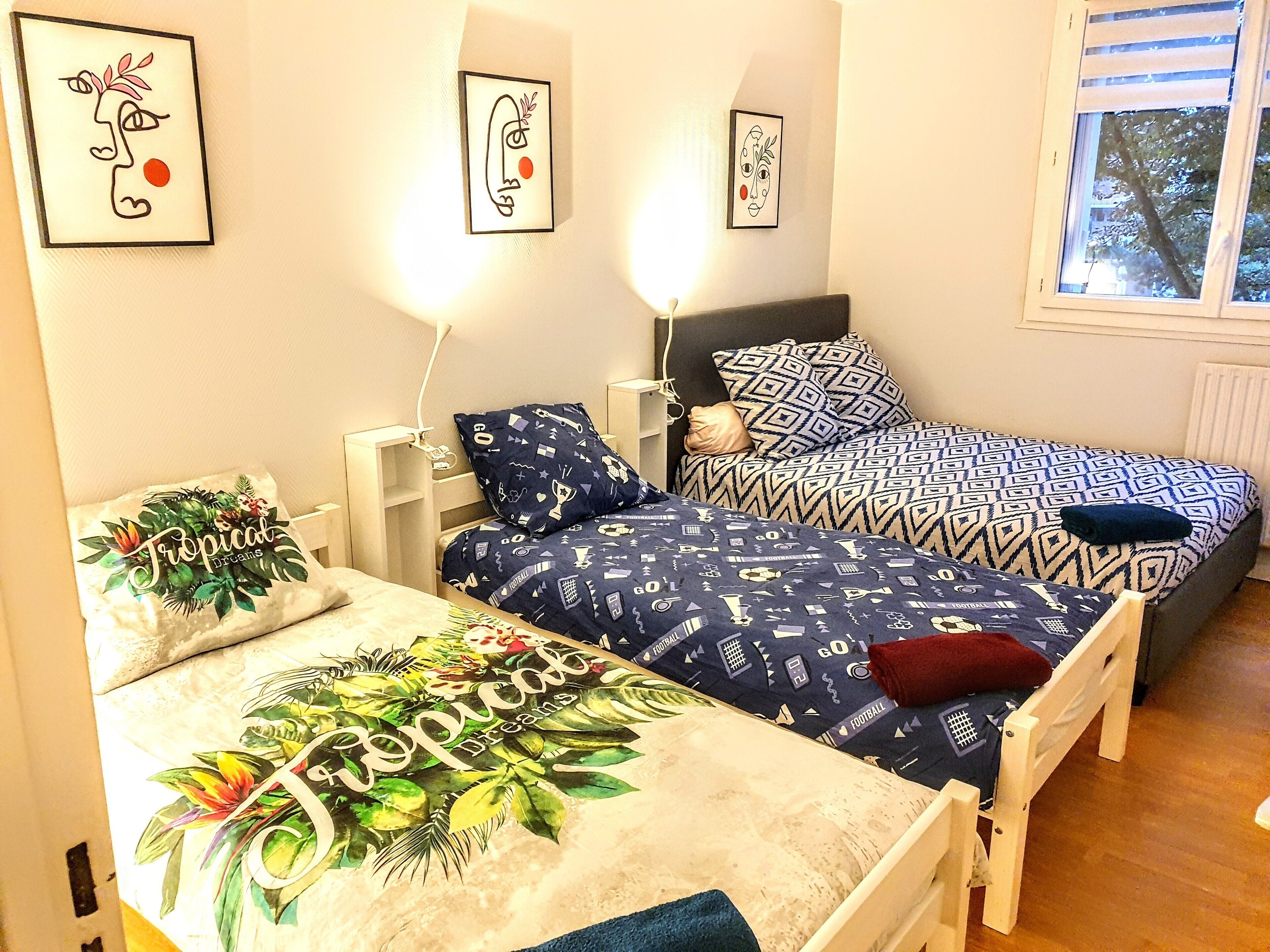 A bedroom with two beds, a nightstand, and wall art.